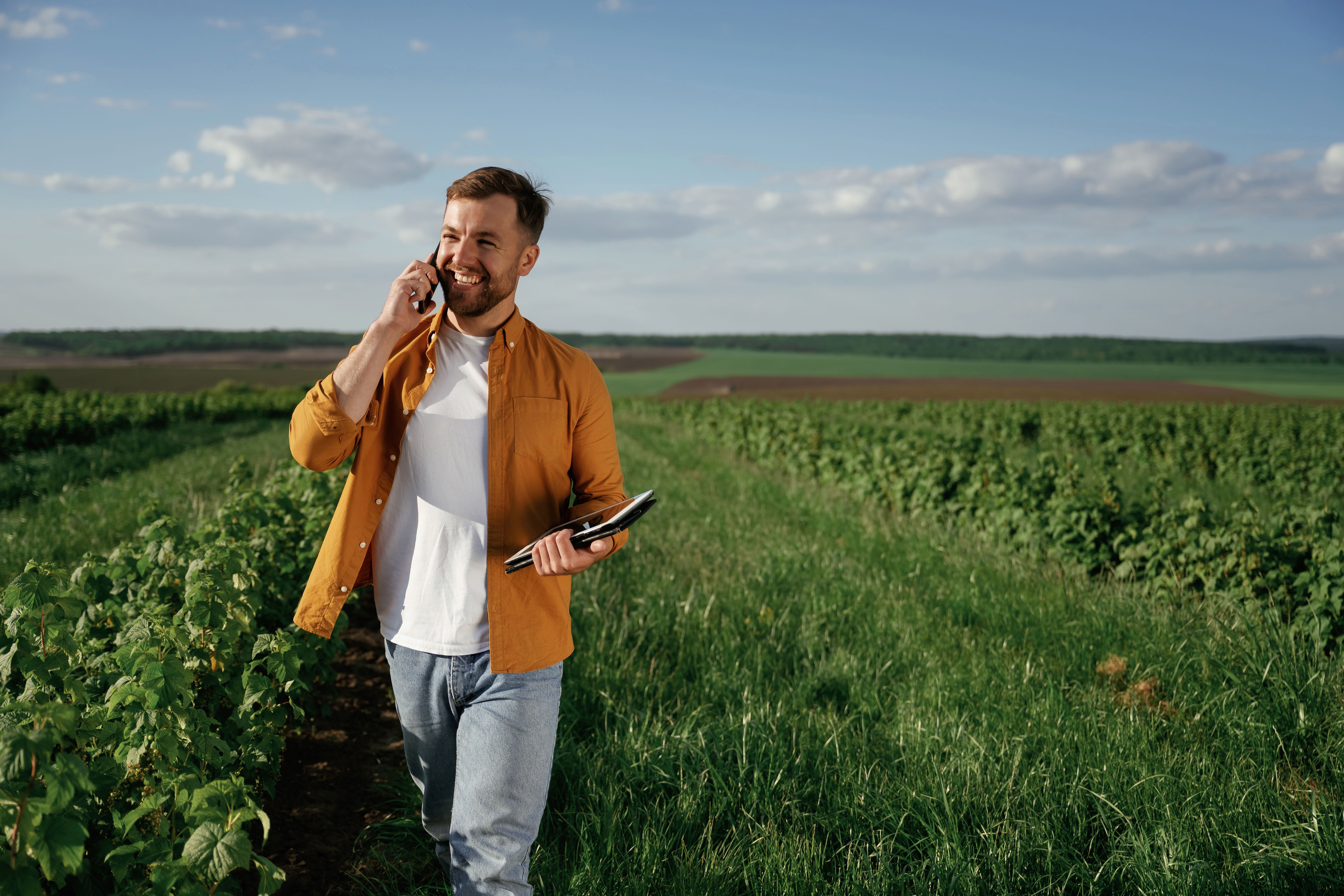 Przedsiębiorca z telefonem na tle zielonego gruntu - klient pożyczki pod zastaw działki Horyzont Capital