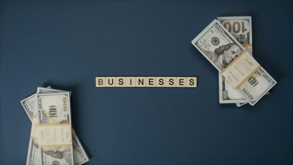 Pliki banknotów na ciemnej powierzchni oraz napis businesses na środku.